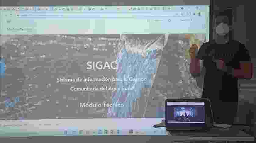 Federico stands in front of a project screen delivering a talk on SIGAC